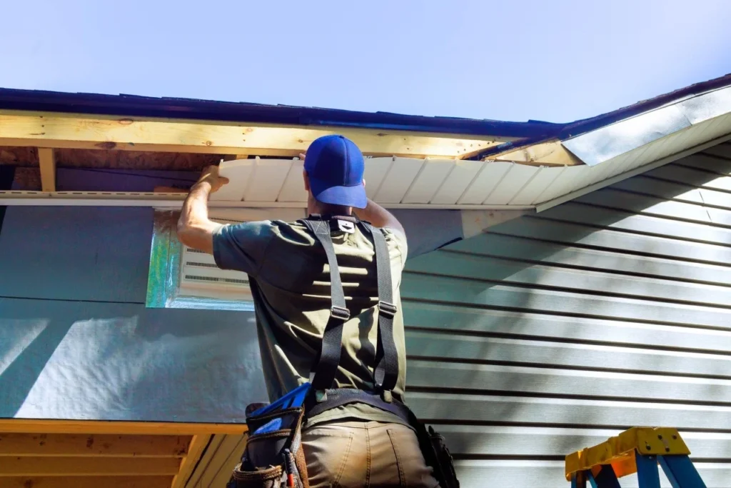 Worker installing soffit panels on a house exterior